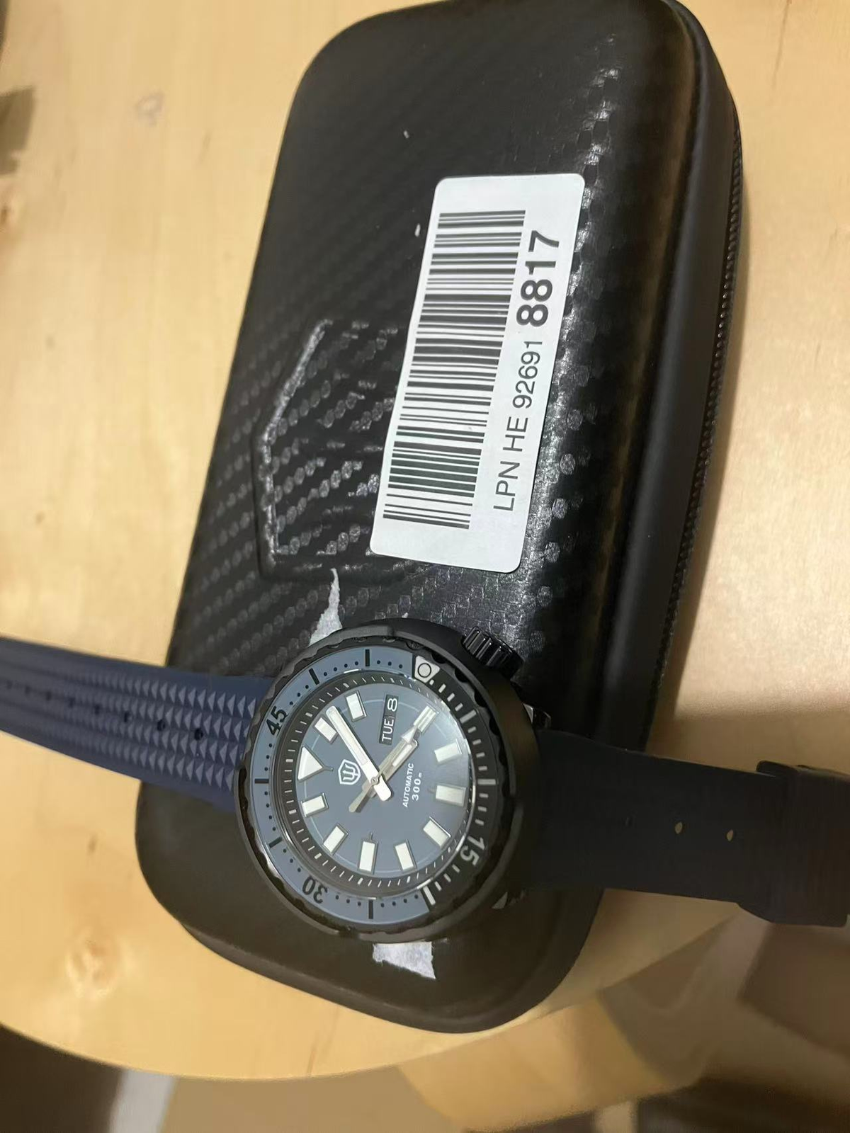 Watchdives Tuna-style dive watch with blue-gray dial, black case, and blue-and-black rubber strap on a black case