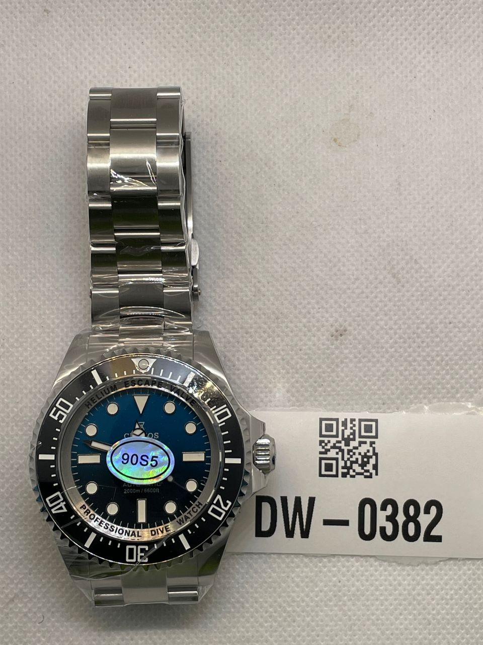 Pre-owned Cronos watch with a blue dial, black dive bezel and silver-tone bracelet, photographed beside tag DW-0382.